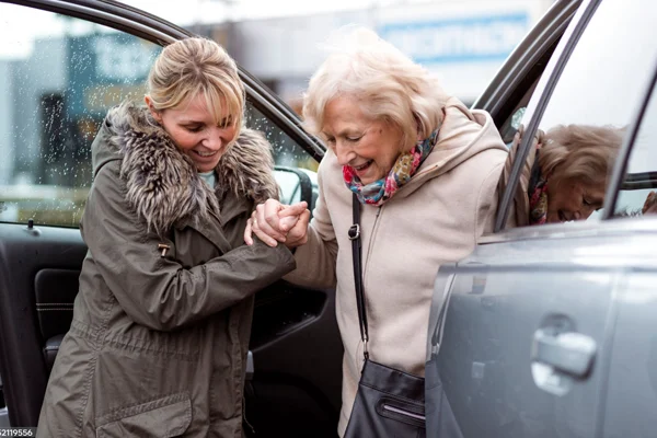 nurse helping old lady out of car